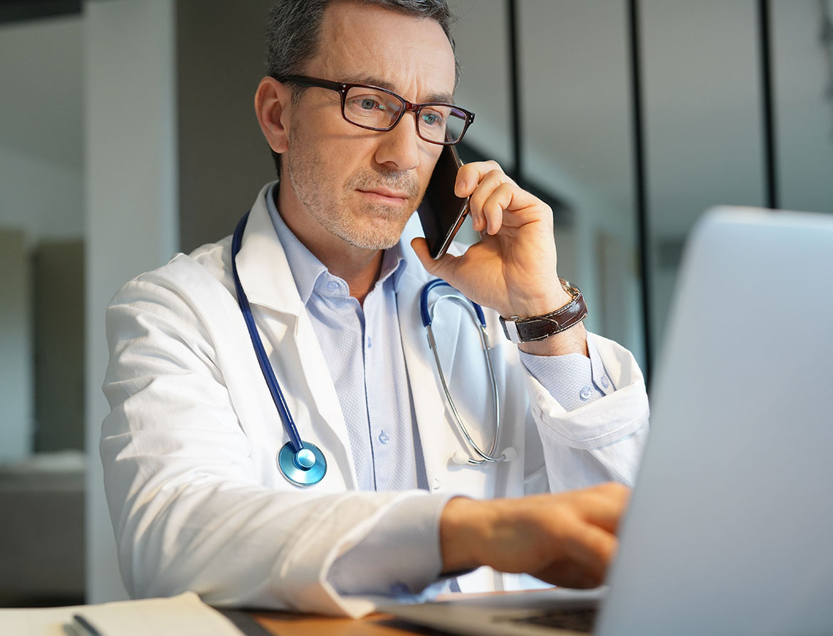 Photo of a doctor on the phone and his computer